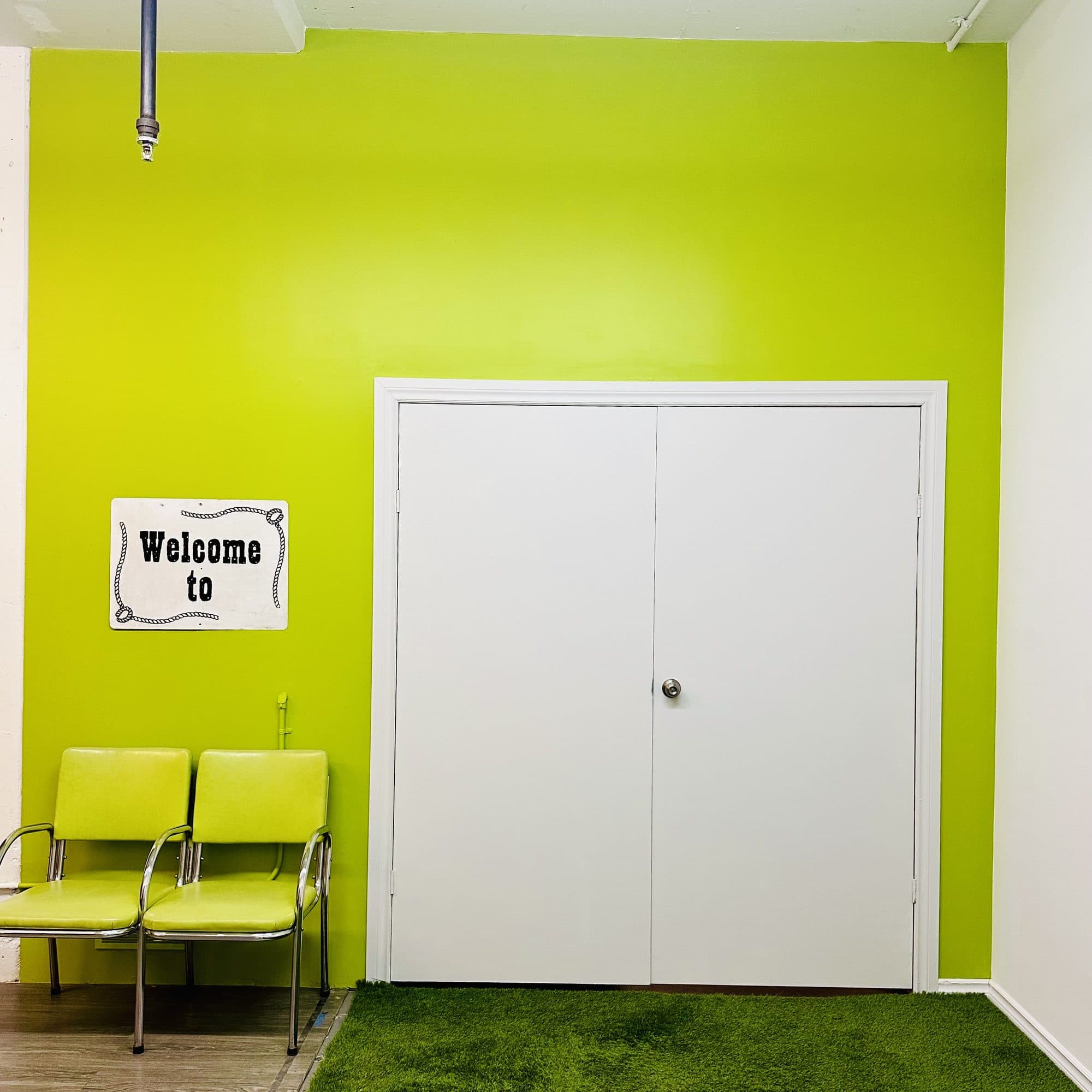 The artverb* front office: green wall, two green chairs and a Welcome to sign
