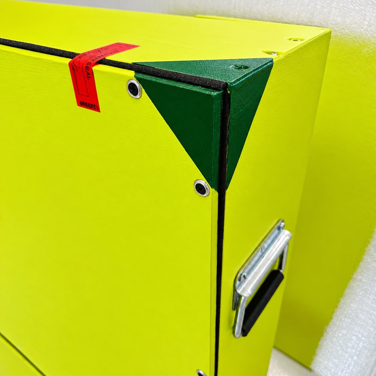 Corner of a painted chartreuse crate with a recessed handle