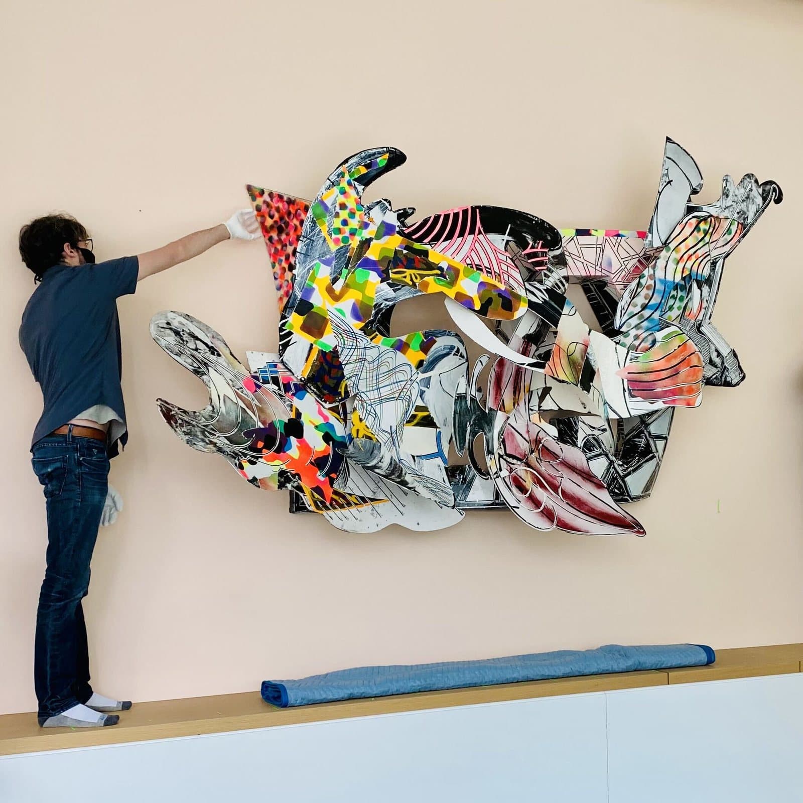 An installer hanging a large wall sculpture