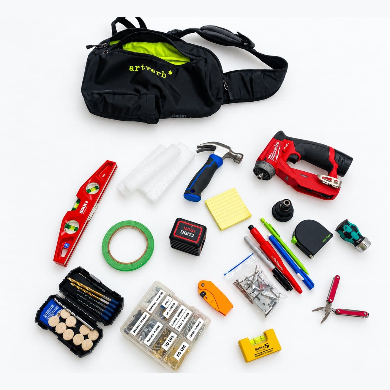 An installer's kit laid out: ArtVerb sling bag, level, hammer, drill, tape, pencils, and hardware