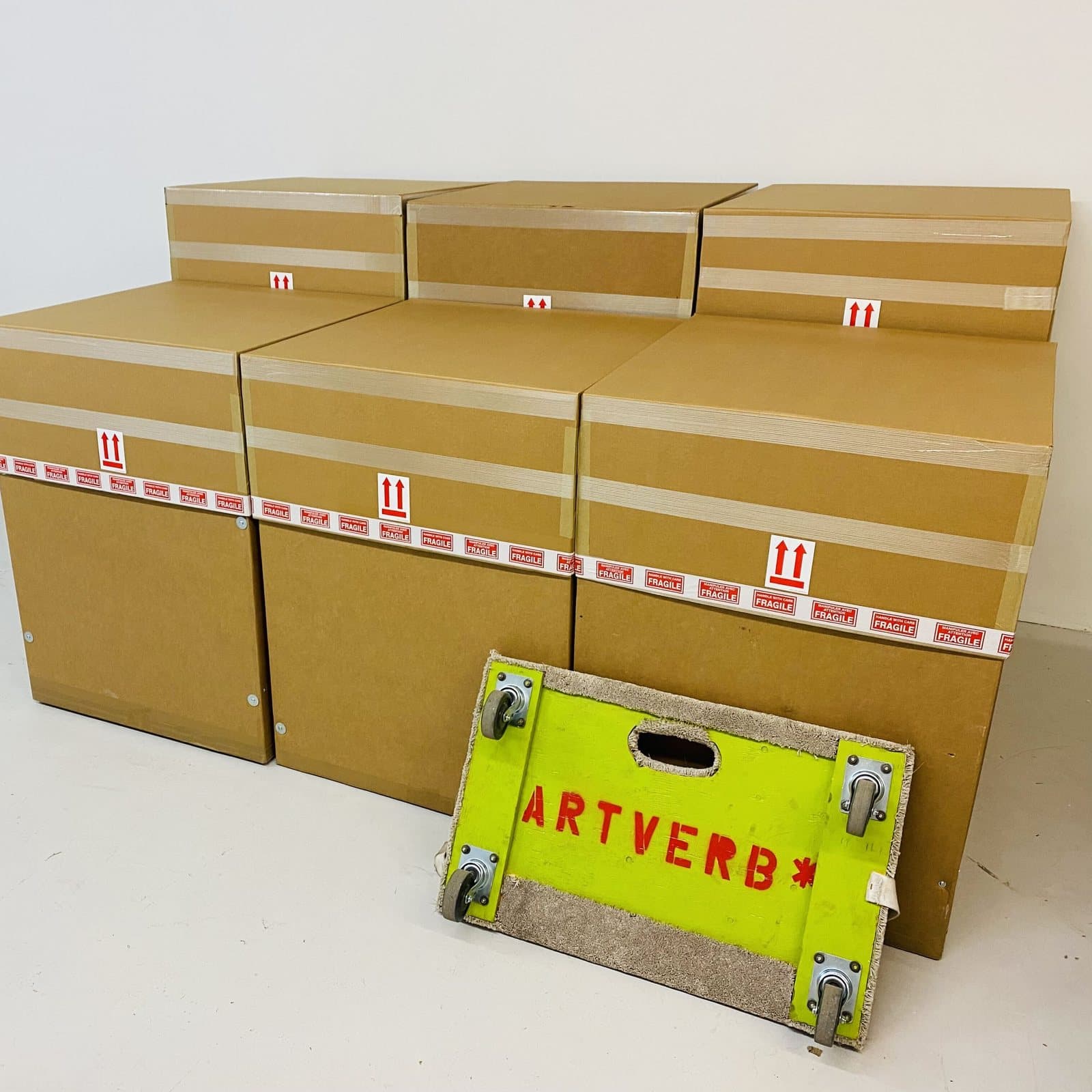 Packed cartons with ArtVerb tape stacked beside a moving dolly