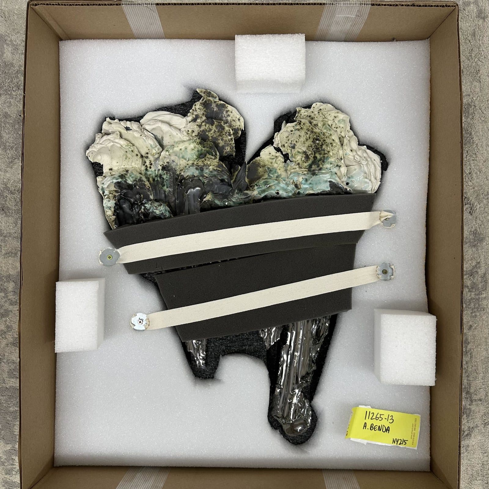 A sculpture strapped into a foam-lined box