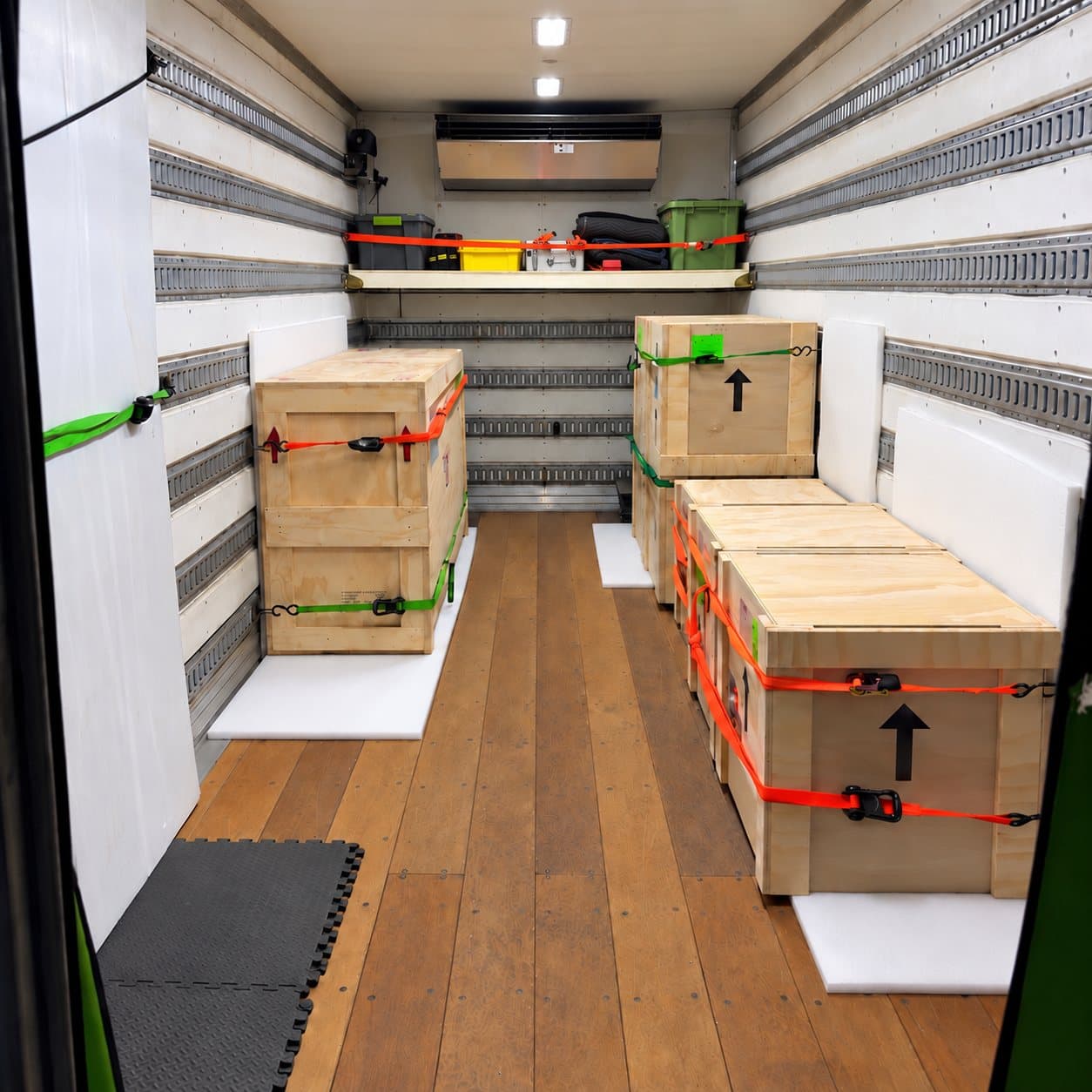Inside an ArtVerb truck: crates strapped to the walls on a wood floor
