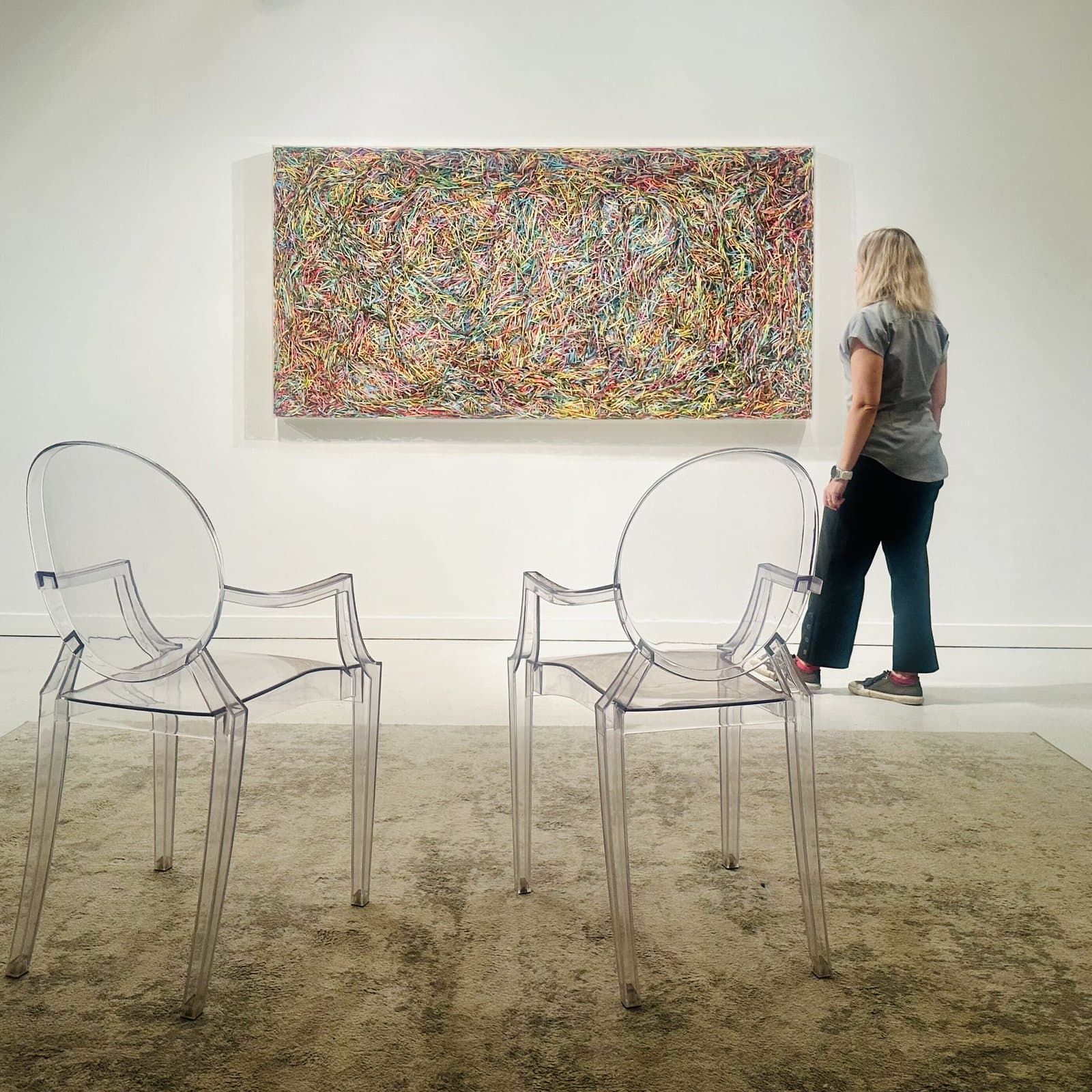A visitor viewing a large abstract painting from the viewing room chairs